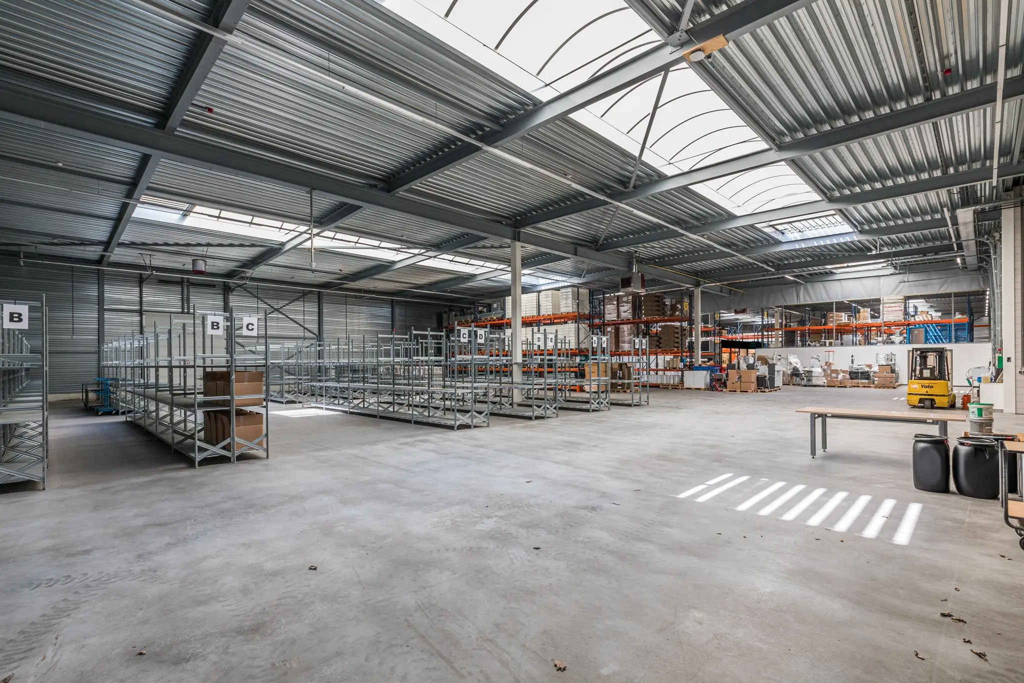 Ruime, moderne bedrijfsloods aan de Laan Blussé van Oud-Alblas met metalen stellages en een heftruck.